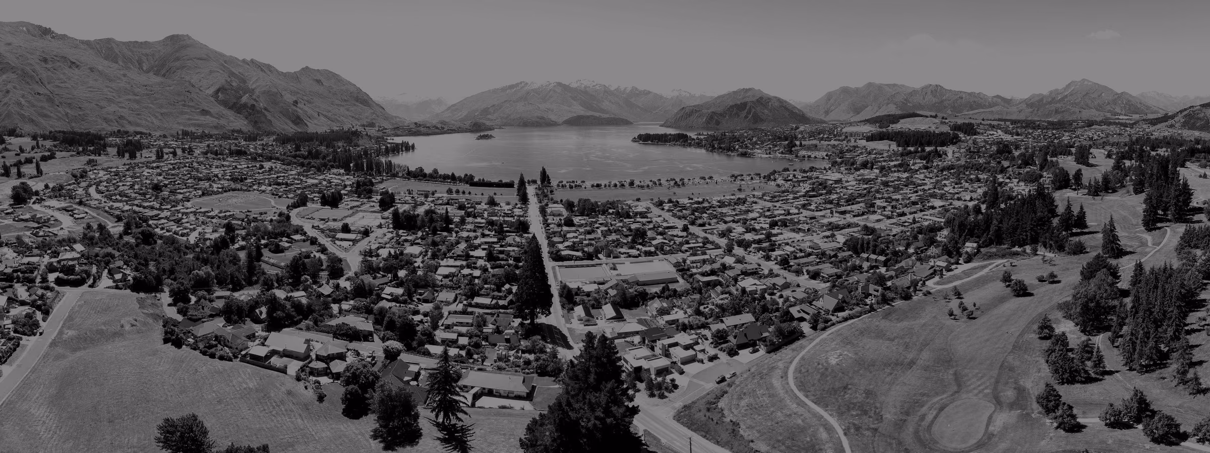 An aerial view over the town of Wānaka towards the lake and mountains.