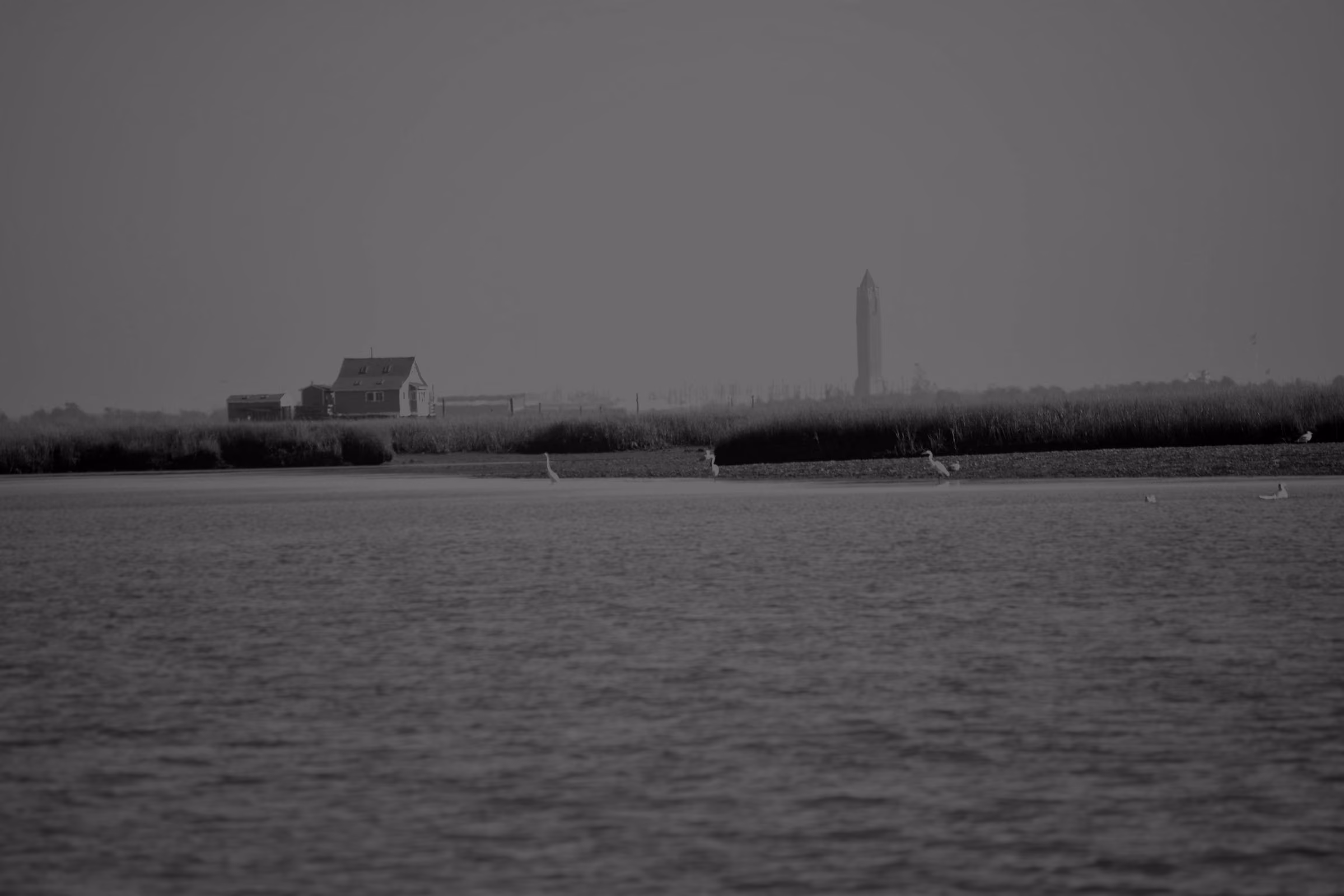 Open blue water in South Oyster Bay with a marsh island and a bay house, and the Jones Beach water tower on the horizon.