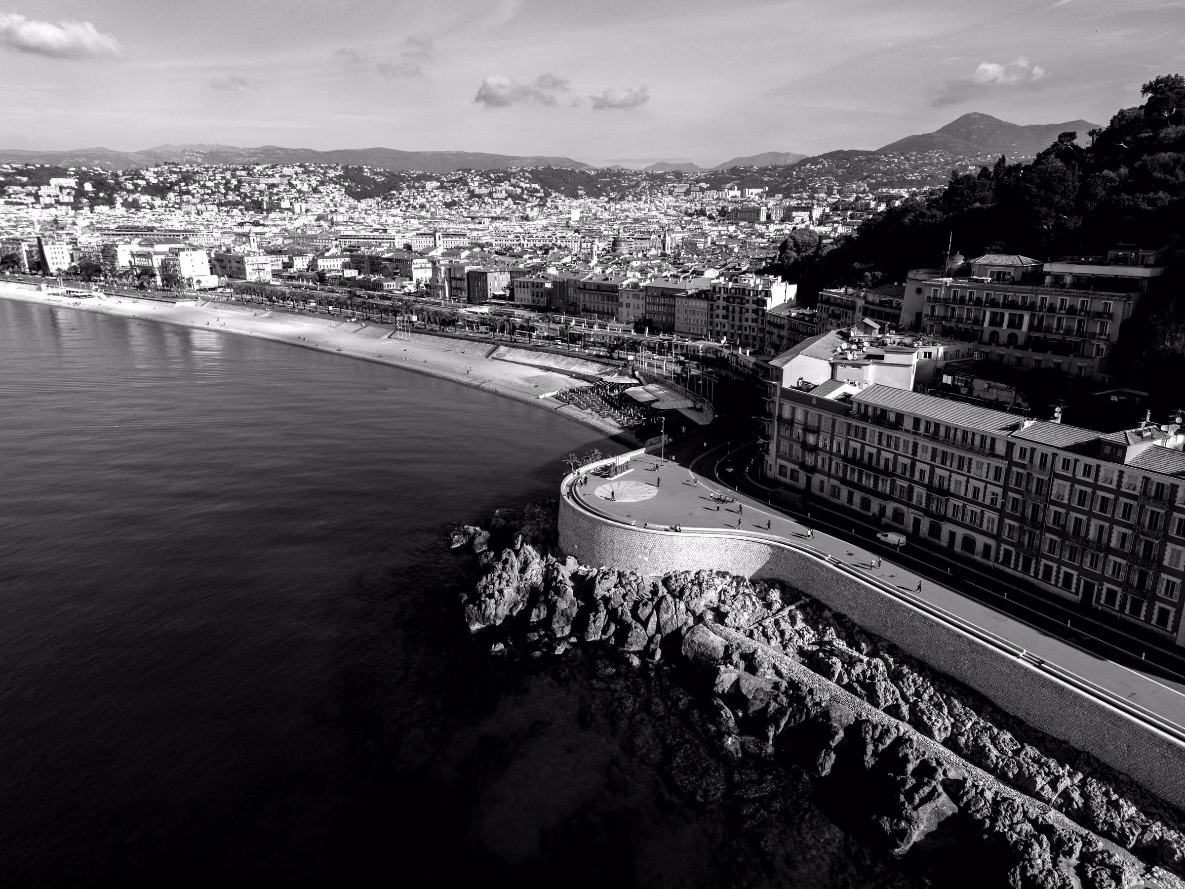 A wide coastal view of the city of Nice along the Mediterranean Sea.