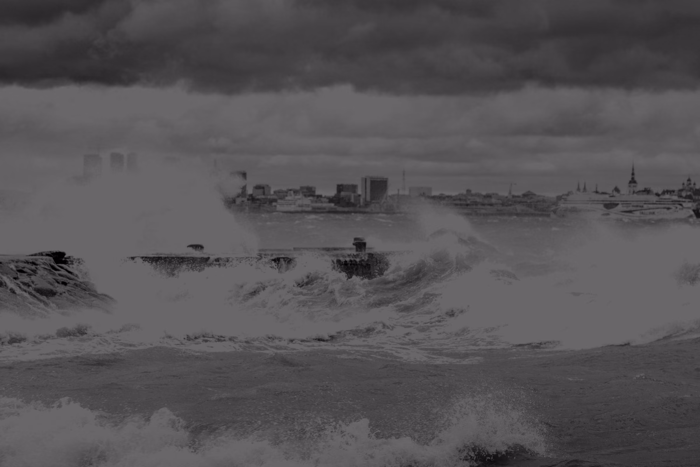 Powerful waves crash against the coastline under a cloudy sky.