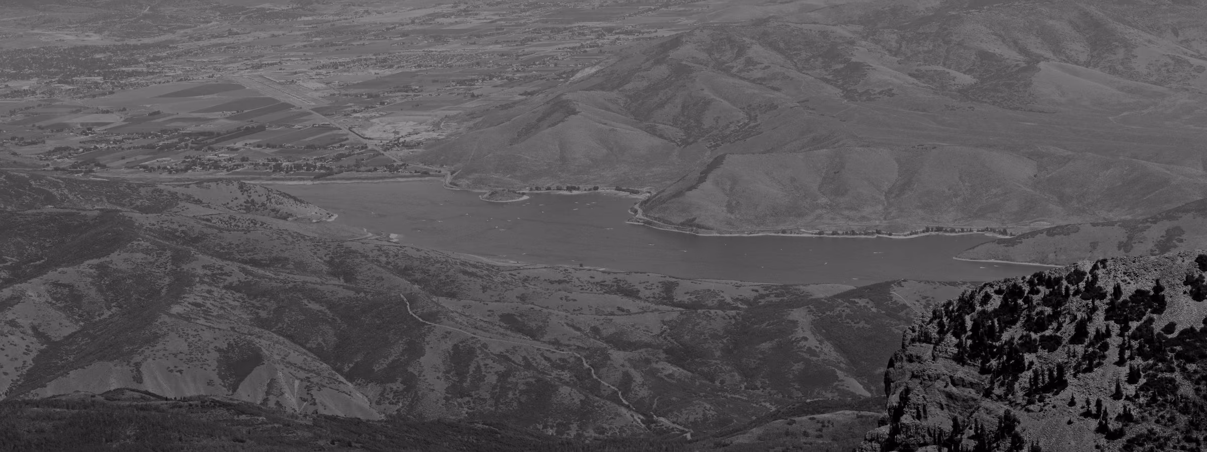 Deer Creek Reservoir in a valley between brown hills, seen from a mountainside.